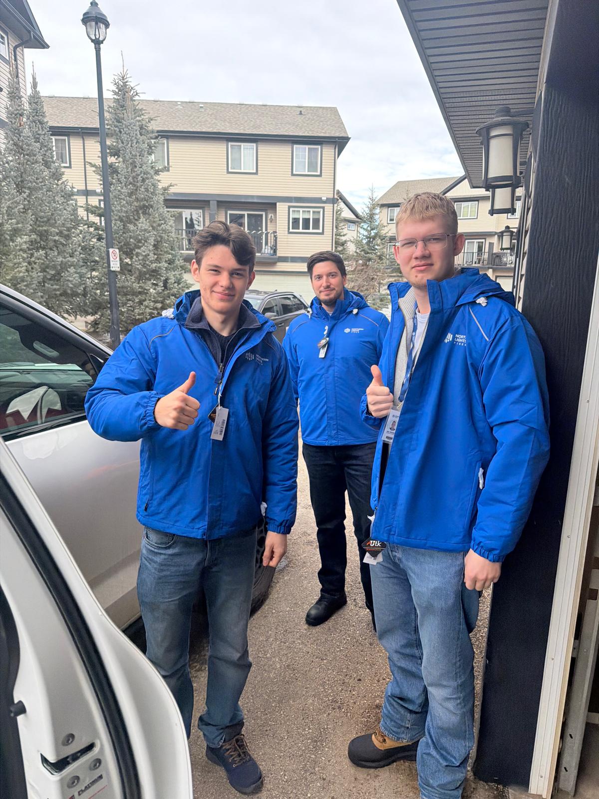 Nordic Sales Group crew in branded fiber jackets giving thumbs up in a neighborhood